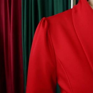 Detailed view of red puff sleeves with structured pleated shoulders and twill fabric texture