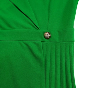 Macro-opname van groene jurk met V-hals, zijplooien en een vintage gouden wapenknop