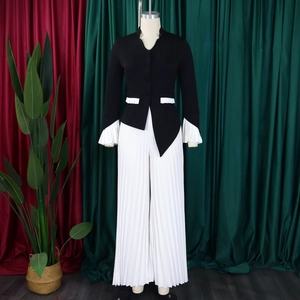 Detail of elegant black blazer with flared white pleated cuffs and matching wide-leg pants