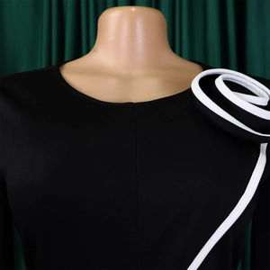 Detail of elegant black dress with 3D black and white floral shoulder design on mannequin