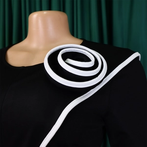 Detail of white spiral 3D flower decoration on the shoulder of a black dress
