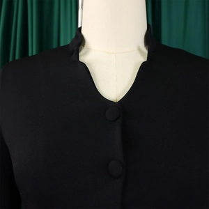 Detail view of black mandarin collar top with fabric buttons and woven texture finish