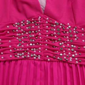 Dettaglio della tuta a pieghe fucsia con perle bianche e decorazioni in argento in vita