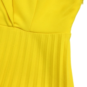 Détail d'une robe jaune vif montrant des plis accordéon fins et une couture à la taille