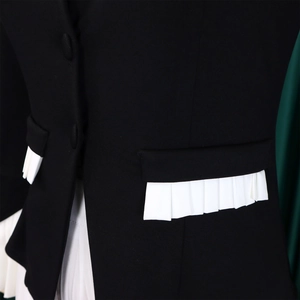Detail of black blazer featuring white pleated hem and elegant fabric covered buttons