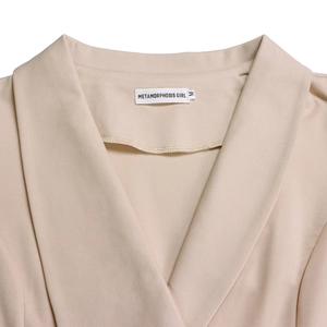 Detailed close-up of apricot lapel neckline and woven texture with brand label