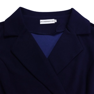 Detail van donkerblauwe geplooide jurk met klassieke reverskraag en merklabel erop