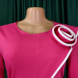 Detail of rose pink dress featuring a large 3D fabric flower with white contrast piping