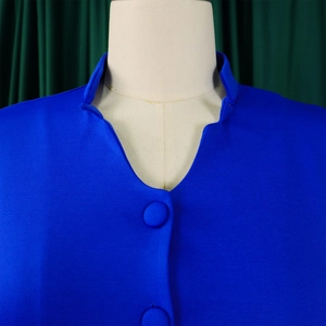 Detail of bright blue flared sleeve top showing V-neckline with fabric-covered buttons