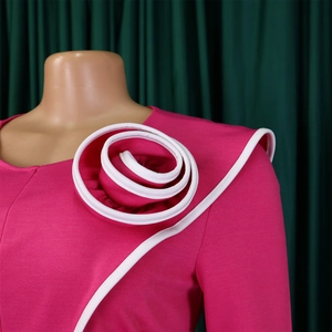 Detail of fuchsia pencil dress with 3D floral accent and white contrast piping