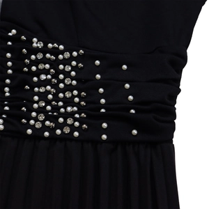 Dettagli delle pieghe in vita con perle bianche e strass lucidi sulla tuta nera elegante