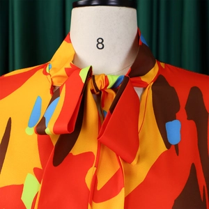 Vue détaillée du col à nouer et de l'imprimé floral abstrait coloré sur le chemisier
