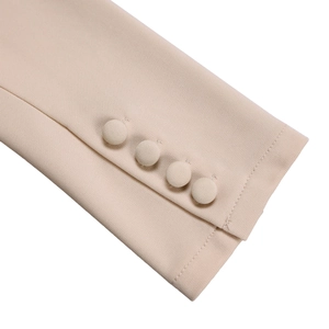 Close-up of beige sleeve cuffs with fabric-covered buttons and high-density woven texture