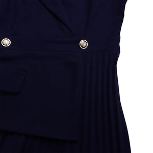 Detail van de marineblauwe jurk met gouden knopen, reverskraag en plooirokontwerp