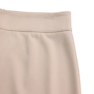 Detailed macro view of beige wide leg trousers showing precise waistline stitching craft