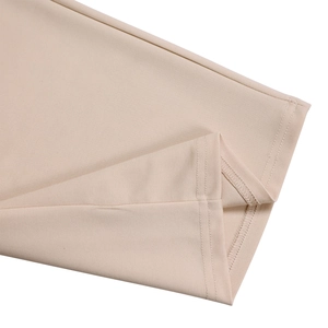 Detailed close-up of double-stitched hem and overlock seam on beige wide-leg trousers