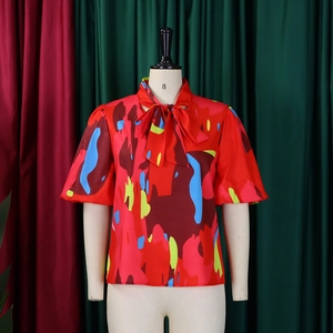 Détail du col à nœud papillon et imprimé abstrait sur le chemisier rouge chic