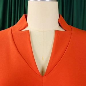 Détail de l'encolure en V d'une robe orange avec des finitions plissées élégantes