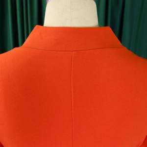 Gros plan détaillé de l'encolure de la robe orange et des coutures du tissu texturé