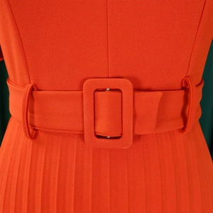 Détail macro de la robe plissée à taille haute avec ceinture à boucle assortie en orange