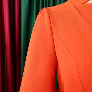 Détail de la couture des manches bouffantes sur une robe plissée orange en tissu crêpe