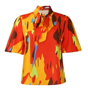 Détail de l'encolure à nœud papillon et imprimé abstrait coloré sur une chemise à manches courtes