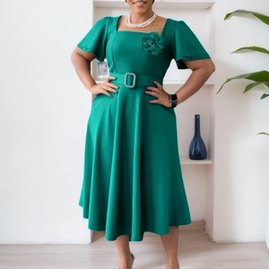 Detail of dark green square neck dress featuring a rhinestone buckle belt and floral brooch