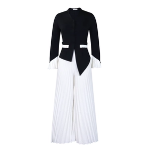 Detailed view of black blazer with white pleated flare sleeves and matching trousers