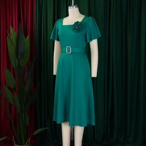 Detail of square neckline with 3D floral accent and ruffle sleeves on a green dress