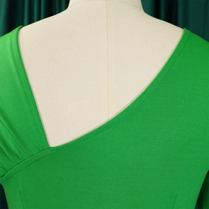Detailweergave van de groene kokerjurk met asymmetrische halslijn en elegante plooien op schouder
