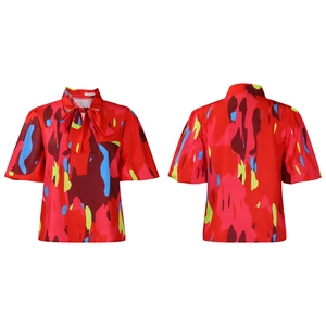 Détail d'un chemisier rouge à imprimé floral avec col à nœud et manches bouffantes