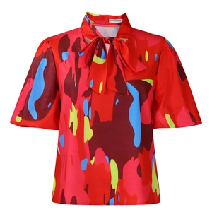 Détail du chemisier rouge fleuri avec grand nœud au col et manches bouffantes