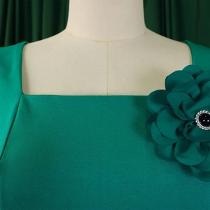 Detail of square neckline with a large fabric flower brooch and black gemstone accent