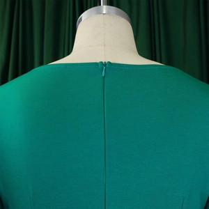 Close-up of emerald green dress back with invisible zipper and textured woven fabric