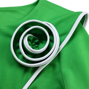 Detailed view of the 3D spiral fabric flower with white piping on a green dress