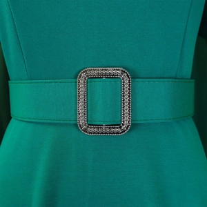 Detail of emerald green high waist dress with a rectangular silver rhinestone buckle belt