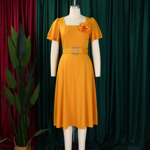 Detail of square neckline and floral accent on ginger yellow maxi dress with ruffles