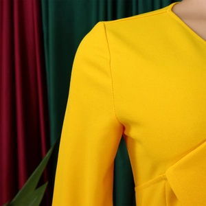Détail de l'encolure en V et du tissu plissé texturé de cette robe jaune vif
