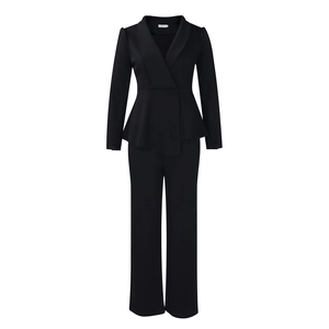 Detail of elegant black peplum top and trousers set with shawl collar and buttoned cuffs