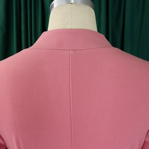 Détail de la robe rose à col en V montrant les plis et la texture du tissu tissé