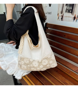 Close-up of cream canvas tote bag featuring intricate lace floral embroidery and ribbon detail