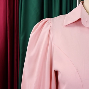 Detail of pink long-sleeve shirt featuring elegant puff shoulder pleats and lapel collar