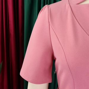 Détail des manches bouffantes roses et des coutures fines sur une robe à col en V