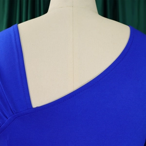 Detail van de asymmetrische halslijn met contraststiksels op een blauwe gebreide jurk