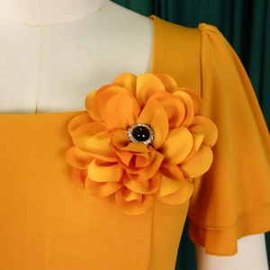 Detail of square neckline with 3D fabric flower and crystal center on orange dress