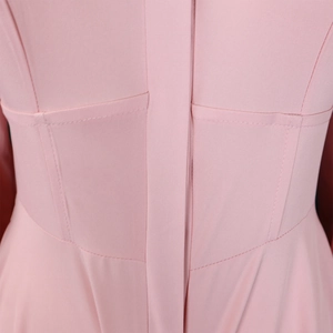 Detail of pink long-sleeve dress showing waist stitching and fine fabric texture