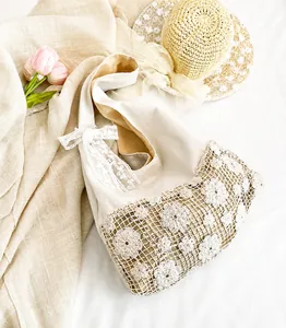 Detail of hollow lace flower tote bag with a decorative ribbon bow on a beige canvas base