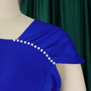 Detail van een koningsblauwe jurk met elegante schouderplooien en witte parelversieringen