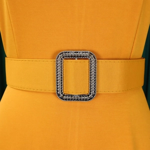 Detailed view of ginger yellow dress featuring a rhinestone-encrusted buckle on the waist belt