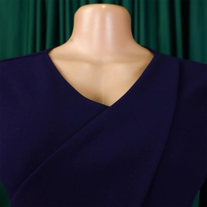 Détail de la robe portefeuille bleu marine à col en V montrant le tissu crêpe texturé